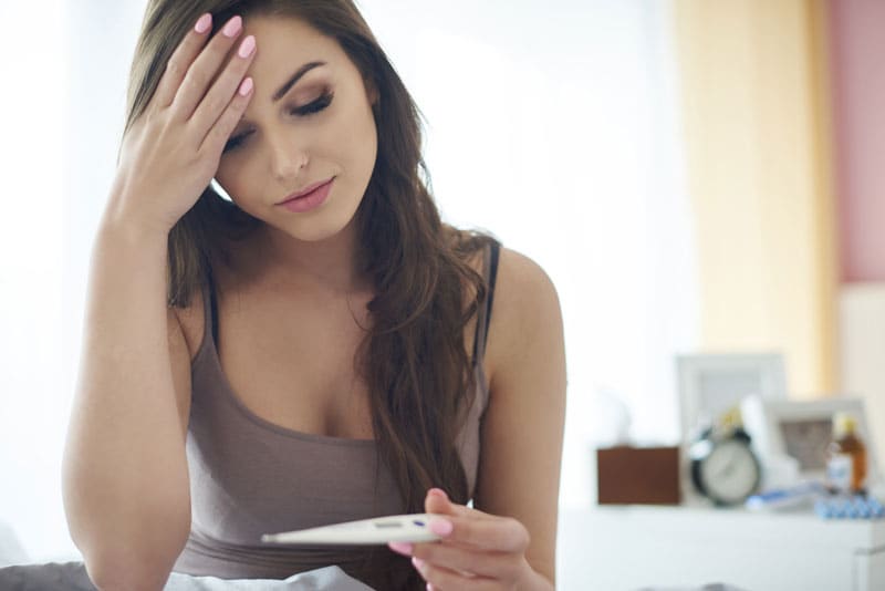 Title Mujer con test de embarazo preocupada porque no le baja la regla y no está embarazada