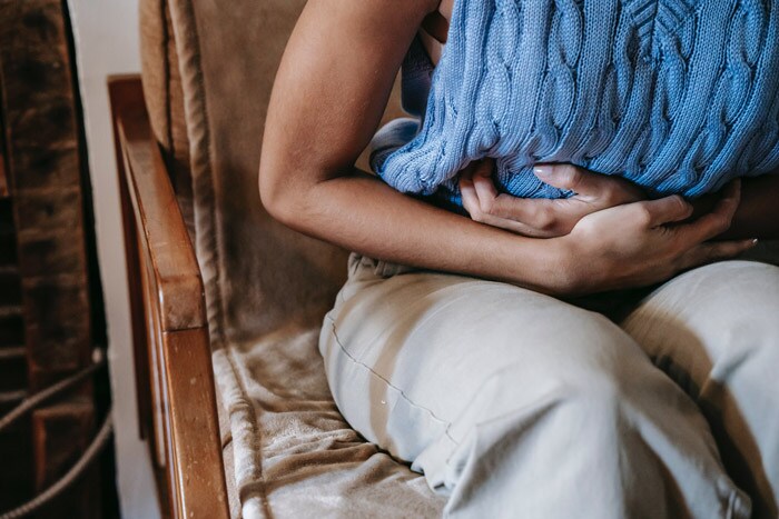 Title Mujer sentada en un sofá con dolor abdominal por ovulación