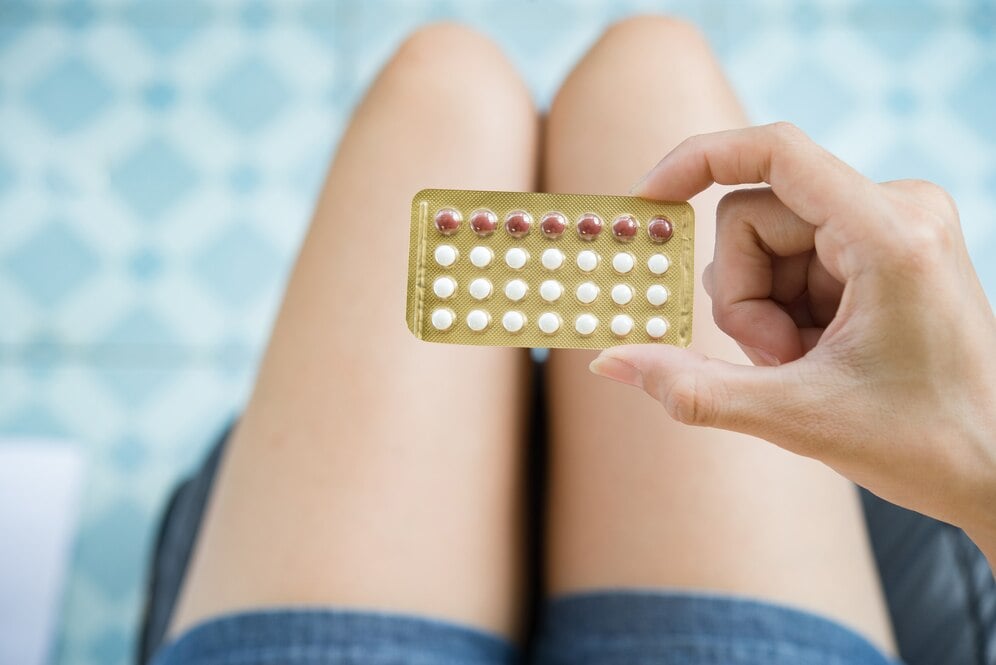 Mujer viendo un blister de píldoras anticonceptivas